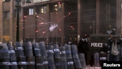 Egyptian riot police take cover as protesters throw flares and stones during clashes in Alexandria on January 25.