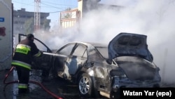 FILE: Firefighters extinguish fire from a vehicle hit by roadside bomb in Helmand in March 2019.