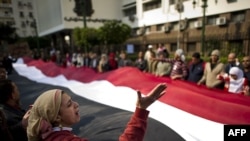 Antigovernment protesters hold a giant Egyptian flag as they shout slogans against President Mubarak outside parliament.