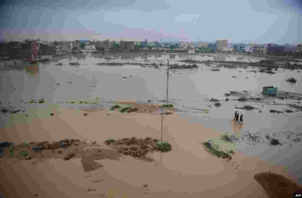 Pakistanis walk through a flooded area in Karachi.