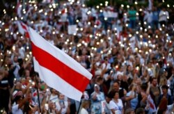 A historical white-red-white flag of Belarus is seen as people attend an opposition demonstration to protest against presidential election results in Minsk on August 18.