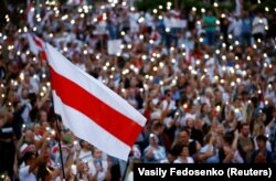 A historical white-red-white flag of Belarus is seen as people attend an opposition demonstration to protest against presidential election results in Minsk on August 18.