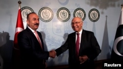 Turkish Foreign Minister Mevlut Cavusoglu (L) shakes hands with Adviser to Pakistan's Prime Minister on National Security and Foreign Affairs, Sartaj Aziz in Islamabad on August 2.