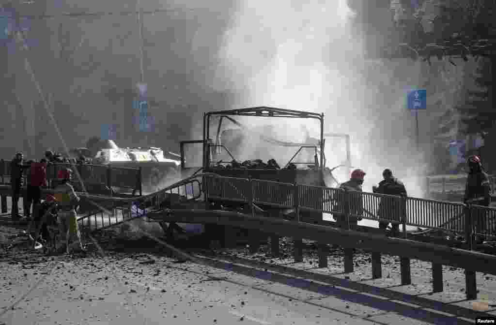 After a night of fighting, Ukrainian servicemen and first responders stand near a damaged vehicle in Kyiv on February 26.