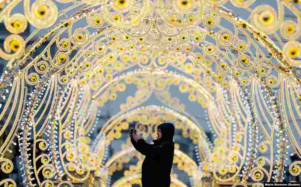 A man takes photos via his smartphone while standing next to street decorations in Moscow.