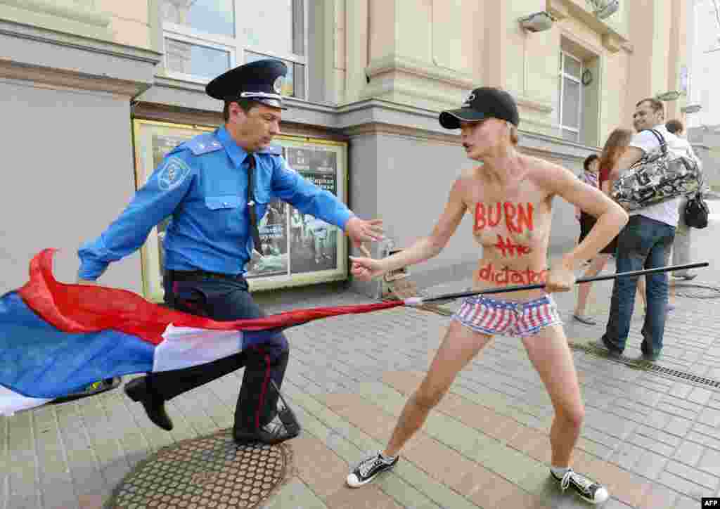  Un polițist încearcă să oprească o activistă Femen în timpul unui protest la Kiev. 