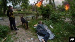 Чоловік лежить на землі, спостерігаючи за своїм палаючим будинком, зруйнованим російською авіацією у Вовчанську, Україна, 11 травня 2024 року. Фото ілюстративне