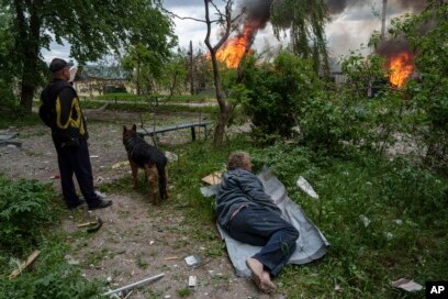 Një burrë shtrihet në tokë teksa e shikon shtëpinë e vet duke u djegur si pasojë e një sulmi rus ajror në Vovçanks, Ukrainë, 11 maj 2024.