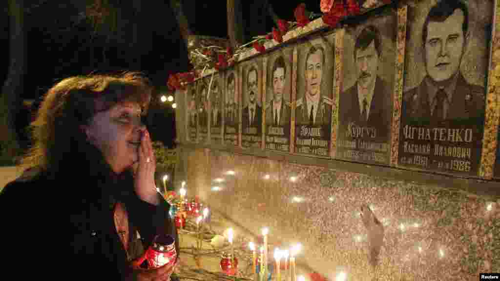 A woman cries in front of a memorial dedicated to firefighters and workers who died after the Chornobyl nuclear disaster during a night service near the Chornobyl plant in the city of Slavutych on April 23, 2012.