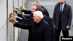 (Front to back:) German President Frank-Walter Steinmeier, Hungarian President Janos Ader, Polish President Andrzej Duda, Slovak President Zuzana Caputova, and Czech President Milos Zeman place roses into a gap in a Berlin Wall memorial during a ceremony marking the 30th anniversary of its fall.