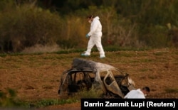 Igazságügyi szakértők vizsgálják a helyszínt, miután egy hatalmas bomba 2017. október 16-án felrobbantotta Daphne Caruana Galizia oknyomozó újságíró autóját azután, hogy elindult otthonról Bidniján