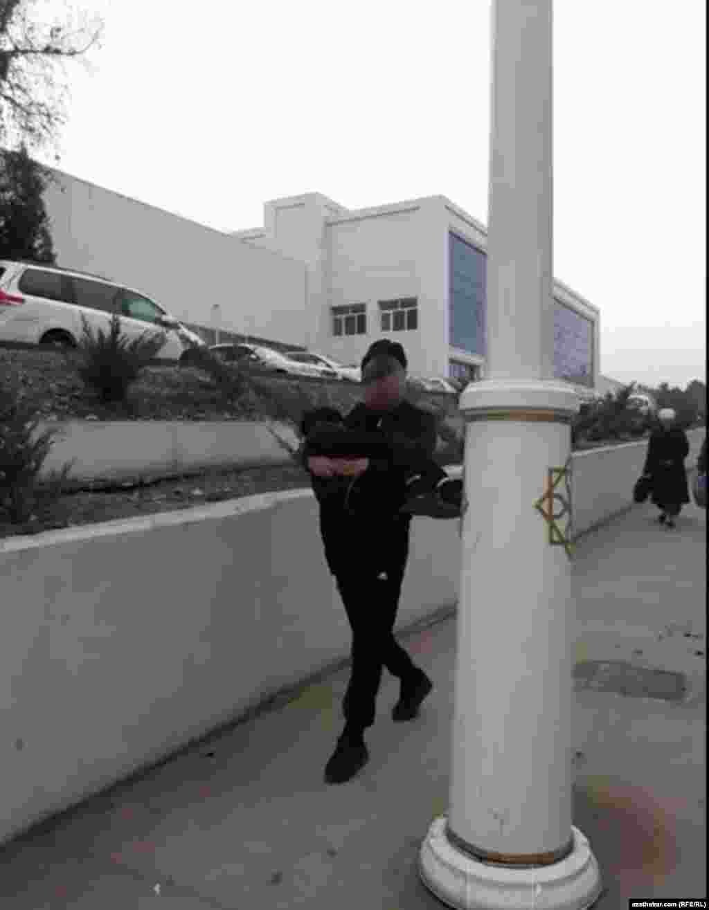 Inisini gujagynda göterip barýan bir ýaş oglan