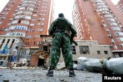 Донецкіде атыстан бүлінген ғимарат жанында тұрған қарулы ресейшіл сепаратист 7 тамыз 2014 жыл.