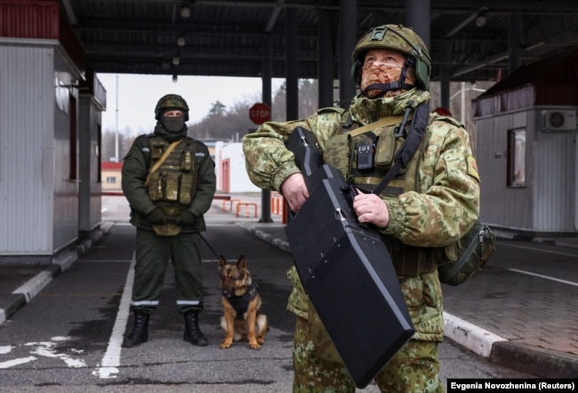 Një ushtar bjellorus qëndron me një pajisje anti-dron në një pikë kalimi kufitar, në kufirin me Ukrainën.