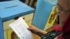 A woman reads her ballot at a polling station during local elections in Chisinau on June 5.