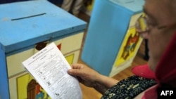 A woman reads her ballot at a polling station during local elections in Chisinau on June 5.