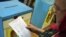 A woman reads her ballot at a polling station during local elections in Chisinau on June 5.