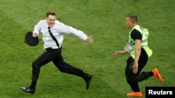 Петро Верзілов (л) тікає від стюарда під час протестної акції на чемпіонаті світу з футболу в 2018 році, архівне фото