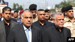 Iraq's Prime Minister Adel Abdel Mahdi (L) and Hadi al-Ameri, leader of the mostly Shiite Hashed al-Shaabi paramilitary units, attend a symbolic funeral ceremony in Baghdad on October 23, 2019 (Photo by AHMAD AL-RUBAYE / AFP)