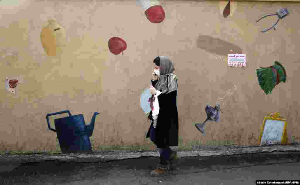 An Iranian woman wearing face mask and protective gloves walks in Tehran. (epa-EFE/Abedin Taherkenareh)