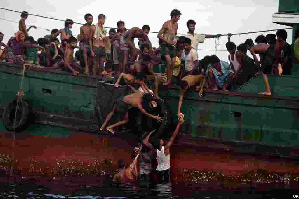 Rohingya migrants from Burma pass food supplies dropped by a Thai Army helicopter to others aboard a boat drifting in waters off the southern island of Koh Lipe in the Andaman Sea on May 14. (AFP/Christophe Archambault)