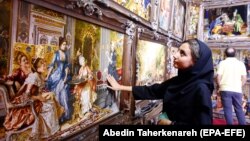زنی در حال بازدید از فرشهای دستباف ایرانی در نمایشگاه موزه فرش ایران