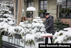 Киевляне расчищают снег напротив дверей своих домов, офисов, магазинов и кафе. Украина. 15 января 2026 года