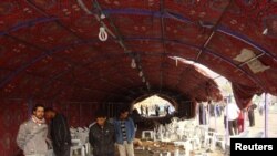 Iraqis inspect the site of a bomb attack inside a funeral tent in Baghdad's Shula district on January 27.
