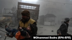 A volunteer carries an injured boy to an ambulance after bombing in the rebel-held city of Douma in eastern Ghouta on February 23.