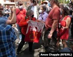 Yekaterina Maldon is jostled by members of the crowd. The sign says “My blood please” above the emblem of the Soviet Union.