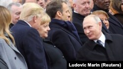 Russian President Vladimir Putin talks with German Chancellor Angela Merkel and U.S. President Donald Trump as they attend a commemoration ceremony for Armistice Day, 100 years after the end of the First World War at the Arc de Triomphe, in Pari