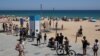 Oamenii stau în rând ca să intre pe una din plajele din Barcelona, Spania. 