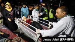 Afghan health workers carry a wounded child after a car bomb targeted a crowded market in Logar Province on July 30.