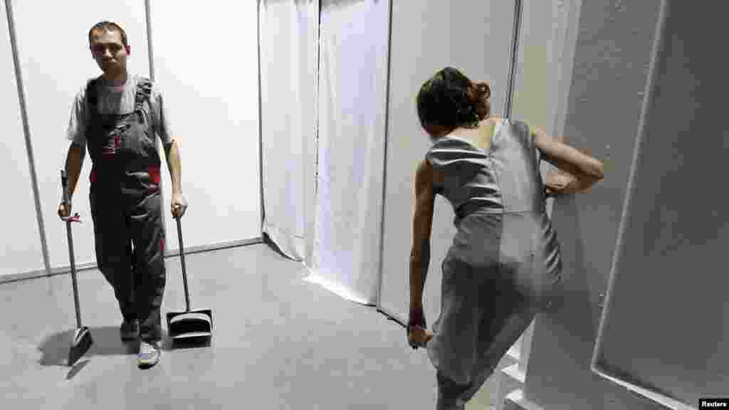 A cleaning worker walks past a model waiting backstage during Ukrainian Fashion Week in Kyiv on October 9. (Reuters/Gleb Garanich)