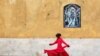 A Pakistani Hindu girl plays near a wall adorned with a religious image outside the Shri Swaminarayan Temple in Karachi. (Reuters/Akhtar Soomro)