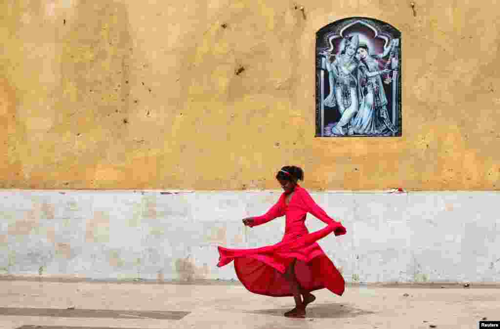 A Pakistani Hindu girl plays near a wall adorned with a religious image outside the Shri Swaminarayan Temple in Karachi. (Reuters/Akhtar Soomro)