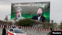 An Afghan man rides on his bicycle past a banner with pictures of Afghan warlord Gulbuddin Hekmatyar in Kabul on May 2.