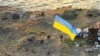 Ukrán katonák kitűzik a kék-sárga nemzeti zászlót a visszafoglalt Kígyó-szigeten az Odessza régióban 2022. július 7-én