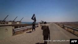 A video grab allegedly shows Islamic State (IS) militants waving a jihadist flag at Mosul Dam on the Tigris River.