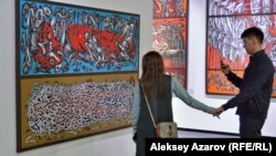 Посетители выставки рассматривают полотно Оразбека Есенбаева «Круговорот еды в природе». Алматы, 10 апреля 2019 года. 