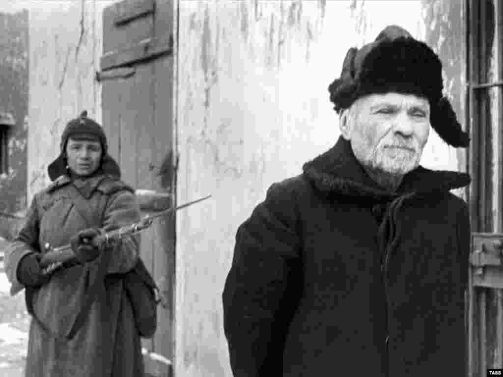 By the 1930s the hat was being phased out and replaced by the warmer ushanka fur caps, as worn by this "traitor" being arrested by a budyonovka-wearing communist in a 1938 propaganda photo. 