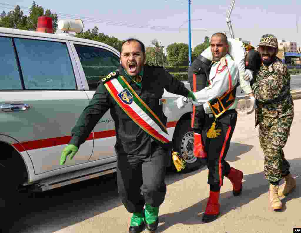 Иранский военный уносит пострадавшего коллегу.