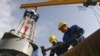 Workers prepare equipment on the drilling tower of the Shakhrinav-1P exploratory well at the Sarikamysh gas field in Tajikistan.