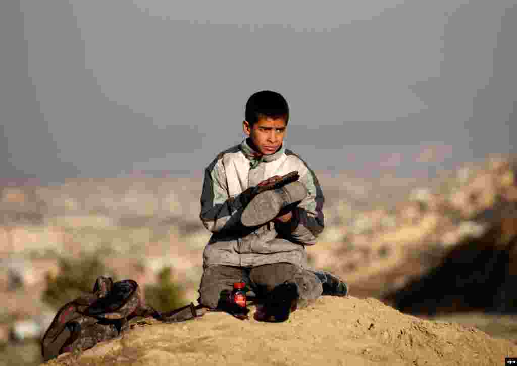 An Afghan shoeshine boy works on a shoe on a roadside in Kabul. (epa/Hedayatullah Amid)