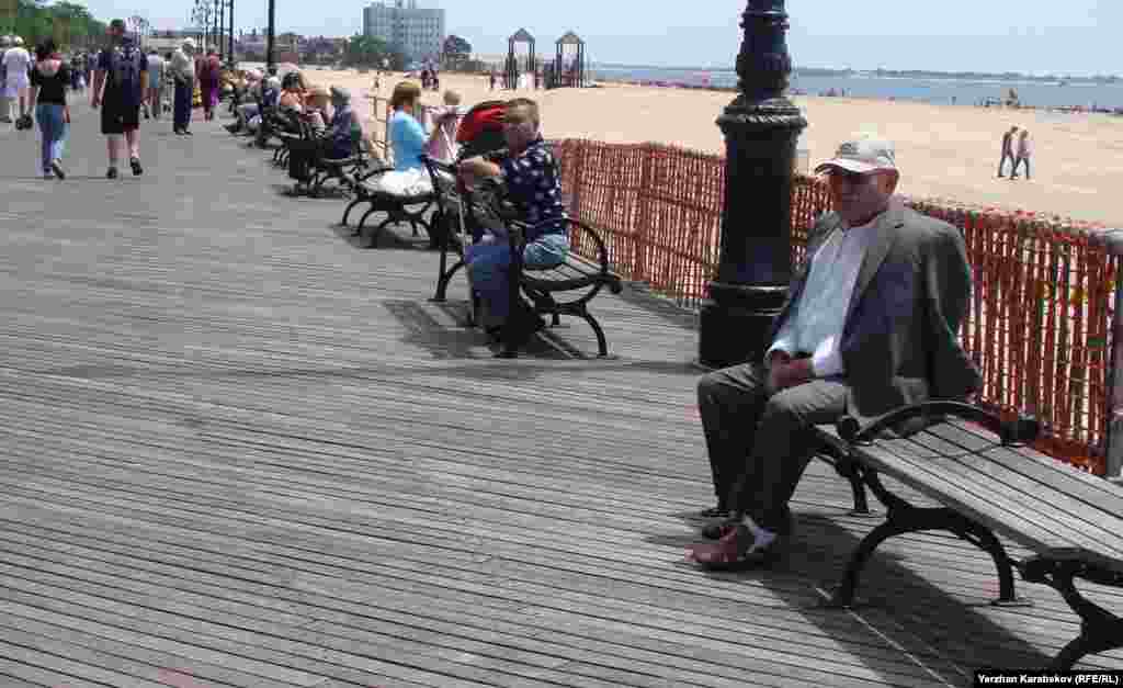 Эмигранты с советским прошлым часами сидят в солнечную погоду на скамейках на популярных в стиле американских приокеанских городов тротуарах, одетых в деревянные доски.