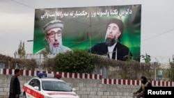 An Afghan man rides on his bicycle past a banner with pictures of Gulbuddin Hekmatyar in Kabul on May 2.