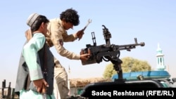 Afghan policeman position a heavy machine gun on a pickup truck to target Taliban positions near the southern Afghan city of Kandahar. 