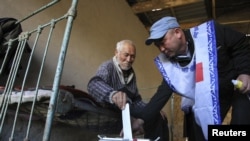 A Kyrgyz man casts his ballot into a portable ballot box at his home during parliamentary elections in the village of Kyzyl-Berlik on October 10.