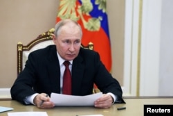 Președintele rus Vladimir Putin prezidează o reuniune cu membrii guvernului, prin legătură video, la Moscova, la 21 iunie.