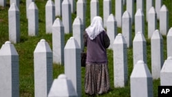 Egy nő sétál a srebrenicai mészárlás áldozatainak sírjai között a Srebrenica melletti potočari emléktemetőben